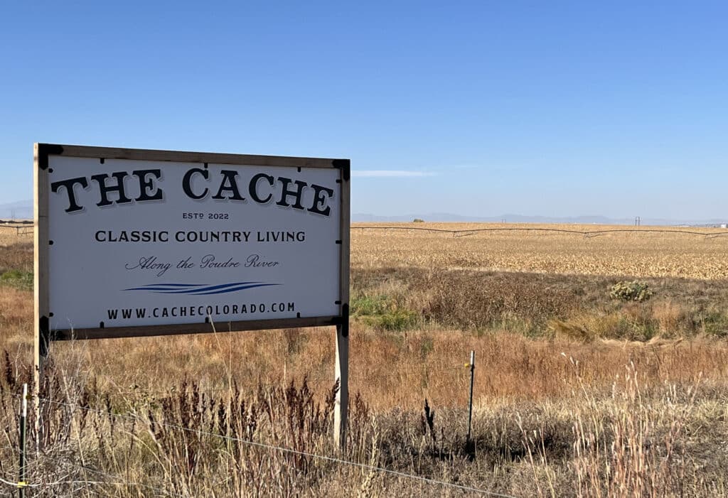 The Cache white and black sign on empty land.