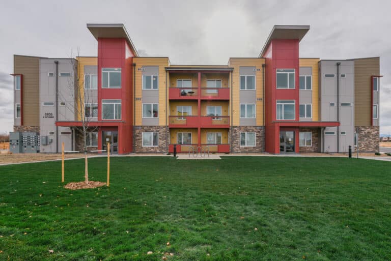 apartment building in yellow and red with green grass