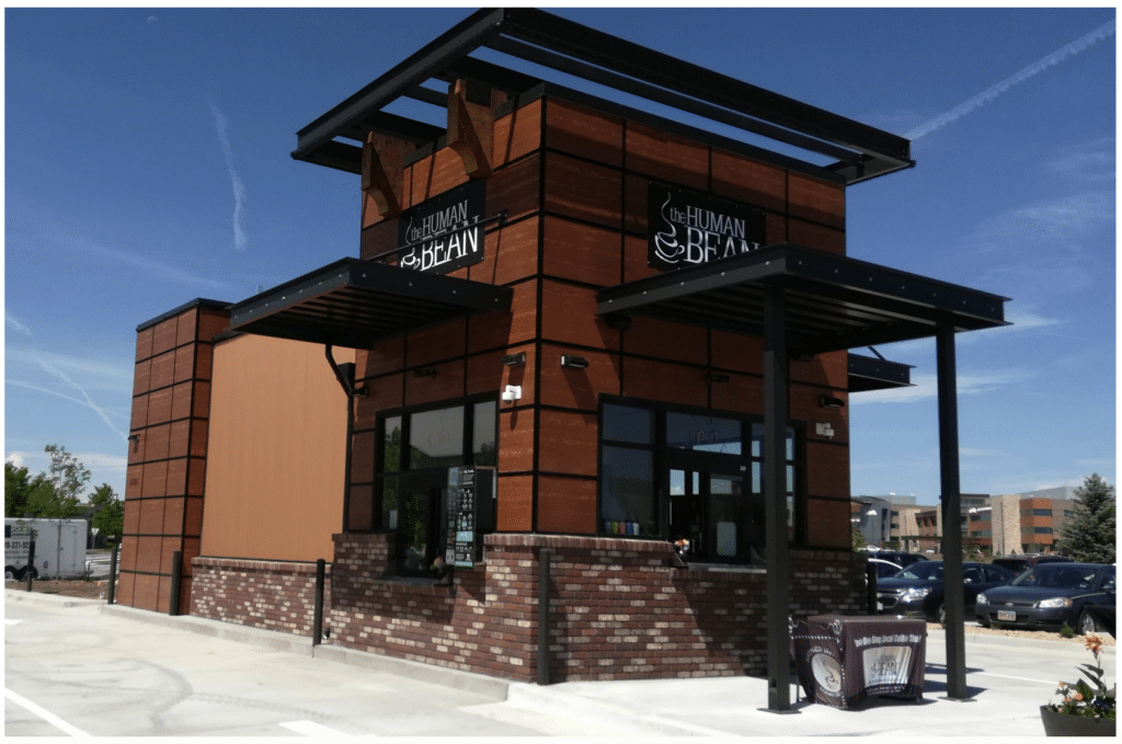 Human Bean - Brown building with break, and awnings against a blue sky